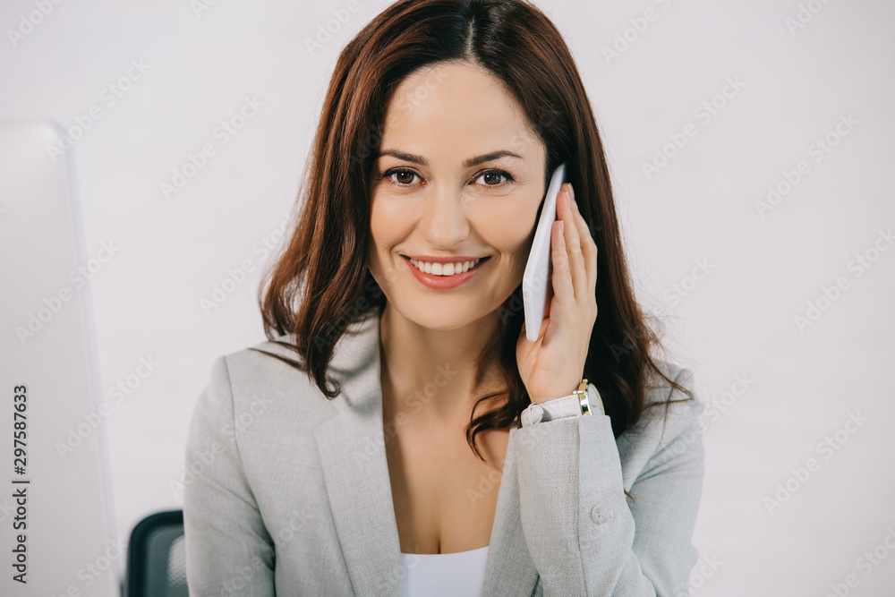 beautiful, smiling secretary looking at camera while talking on smartphone beautiful, smiling secretary looking at camera while talking on smartphone
