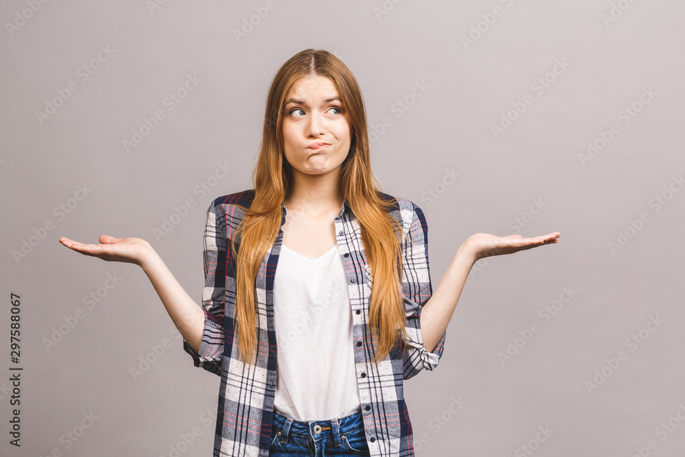 Beautiful serious young woman pointing away and looking isolated over grey background. Free copyspace for product or text. Beautiful serious young woman pointing away and looking isolated over grey background. Free copyspace for product or text.