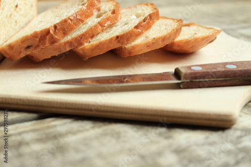  Fresh grain bread, sliced, lies on a wooden board. Nearby lies a knife.