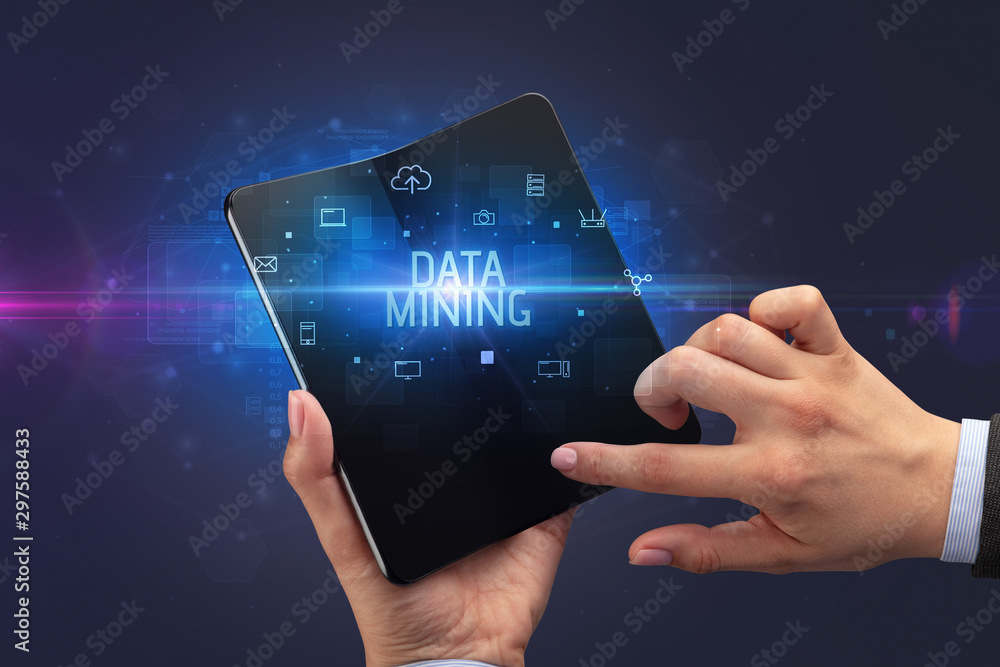 Businessman holding a foldable smartphone with DATA MINING inscription, cyber security concept Businessman holding a foldable smartphone with DATA MINING inscription, cyber security concept