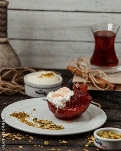 glazed quince topped with ice cream and clove on plate with pistachios