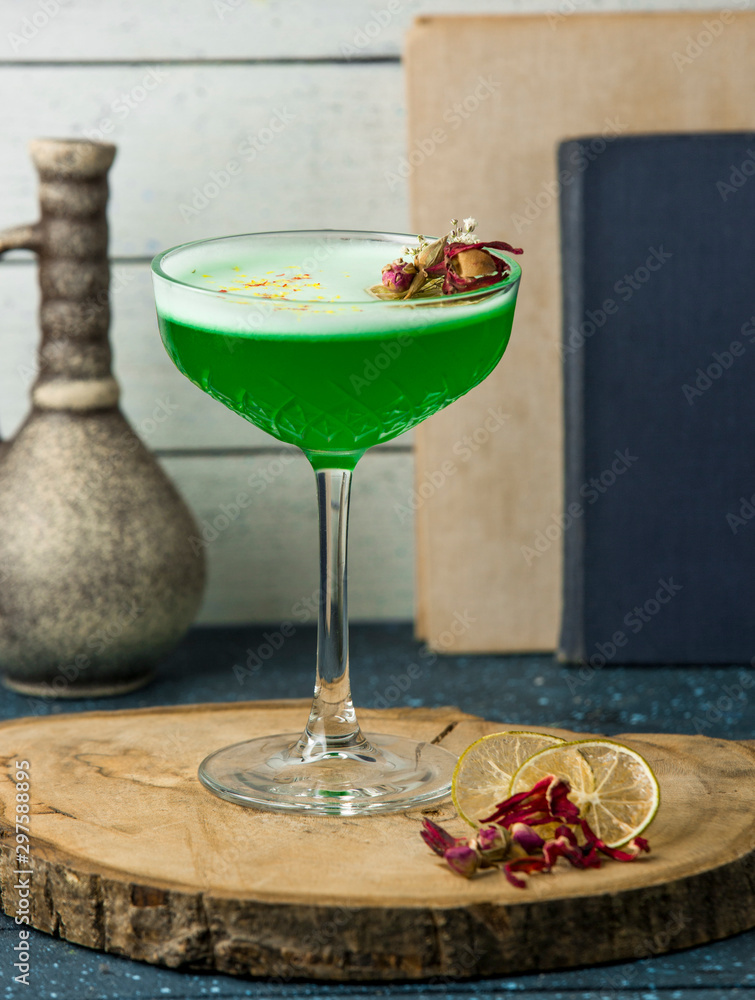 green cocktail garnished with dried rose buds in crystal glass green cocktail garnished with dried rose buds in crystal glass
