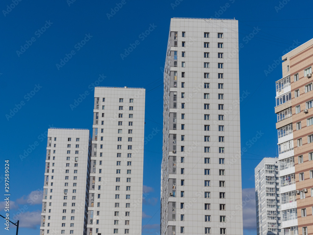 New white high-rise residential buildings against the blue sky. The theme of an emerging housing market under construction