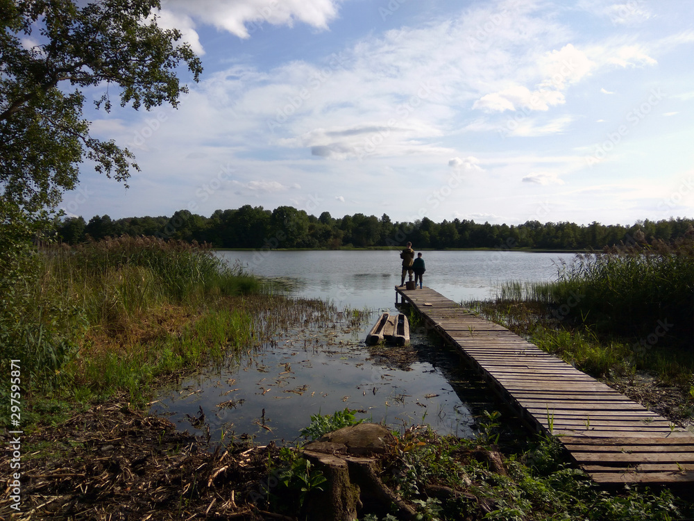 lake with a bridge for fishing in the summer against a blue sky