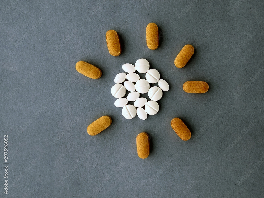 photo white pills laid out in the shape of the sun on a blue background