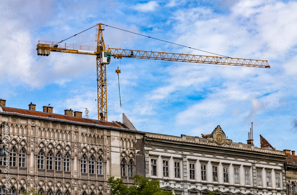 Big building crane on the background of old vintage baroque building in Budapest.