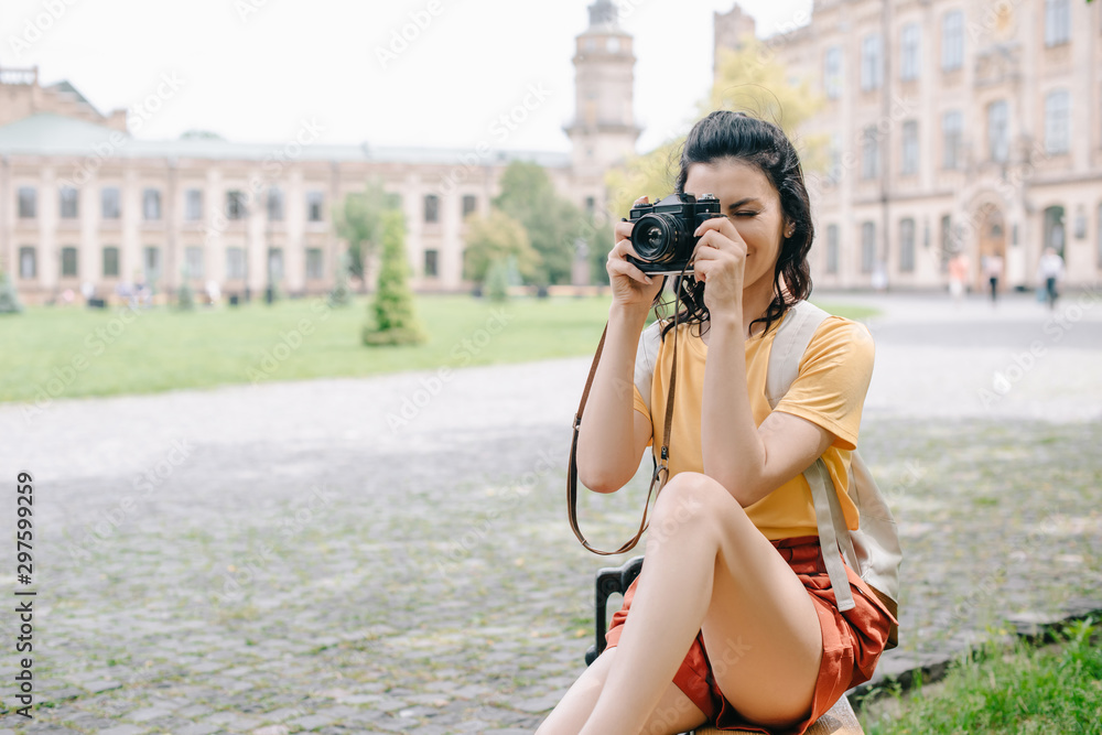 young woman covering face while taking photo near university