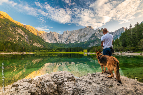 Tattoed Man with Dog Looking at Beautiful Lake and Mountains. Outdoor Active  Lifestyle