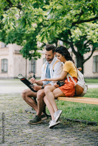 cheerful woman gesturing near map and handsome man