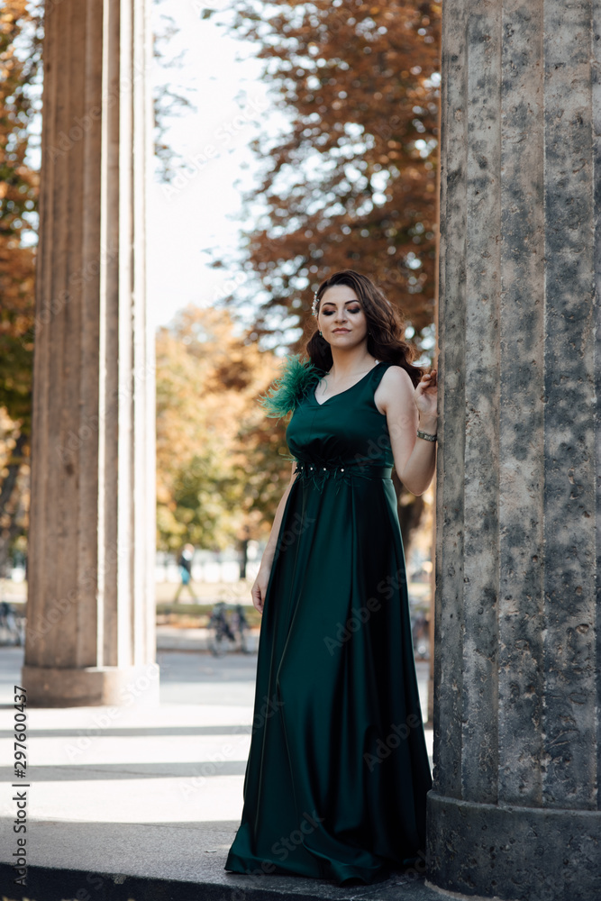 Young pretty lady in green dress. Hair. Beautiful brunette Girl. Sexy woman with wavy long hair. Beauty model. Hairstyle. Sexy girl posing. Female fashion. Young beautiful stylish girl walking 