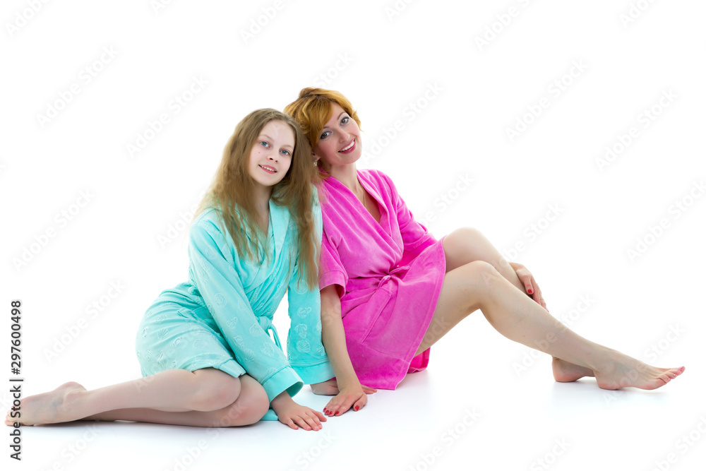 Daughter and mother in bathrobes posing in the studio. The conce Daughter and mother in bathrobes posing in the studio. The conce