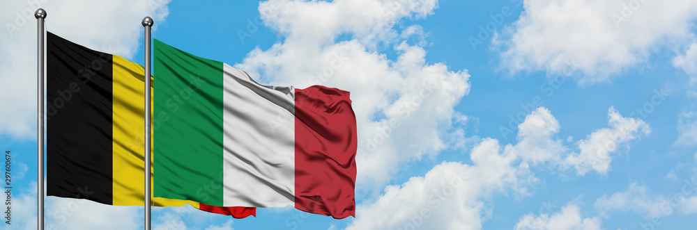 Obraz premium Belgium and Italy flag waving in the wind against white cloudy blue sky together. Diplomacy concept, international relations.