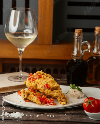 crispy fried fish garnished with tomato cubes, served with herb sauce