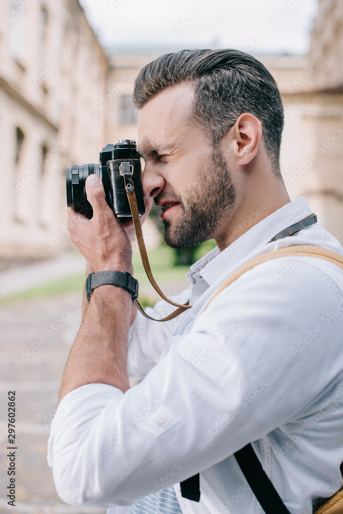 side view of bearded man taking photo on digital camera
