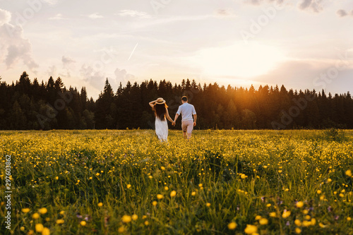 Running loving couple in the field. Sunset.
