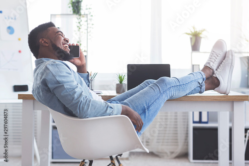 Foto Employee putting his legs on table and talking on phone