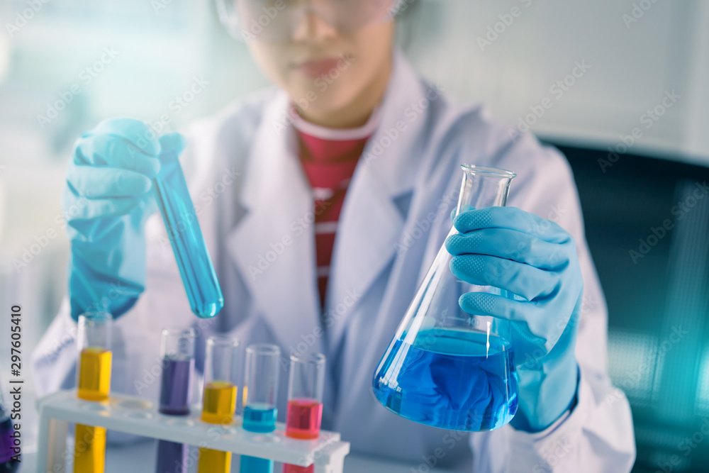 Fototapeta premium Young Asian medical technologist female making testing with test tube while doing research in science laboratory