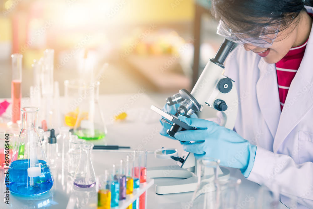 Fototapeta premium Young Asian medical technologist female making testing with test tube while doing research in science laboratory