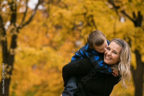 Cute mother and son piggy back in autumn color