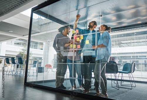 Diverse businesspeople brainstorming together on a glass wall