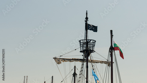 mast ship with a pirate flag on a background of clear blue sky photo