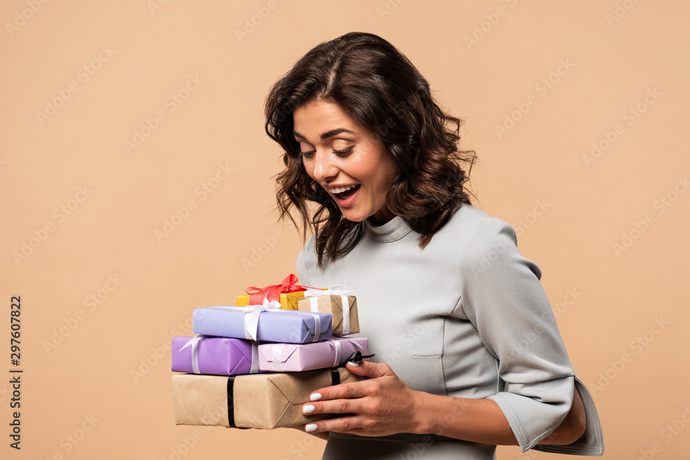smiling woman in grey dress holding gifts on beige background smiling woman in grey dress holding gifts on beige background