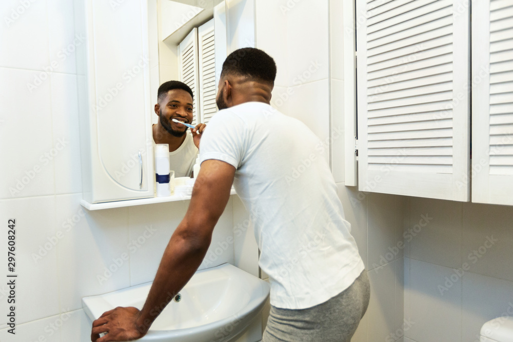 African american man brushing teeth in bathroom African american man brushing teeth in bathroom