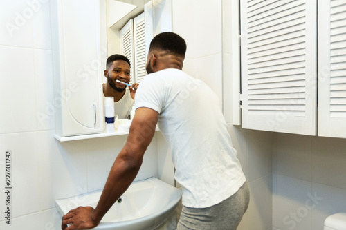 African american man brushing teeth in bathroom