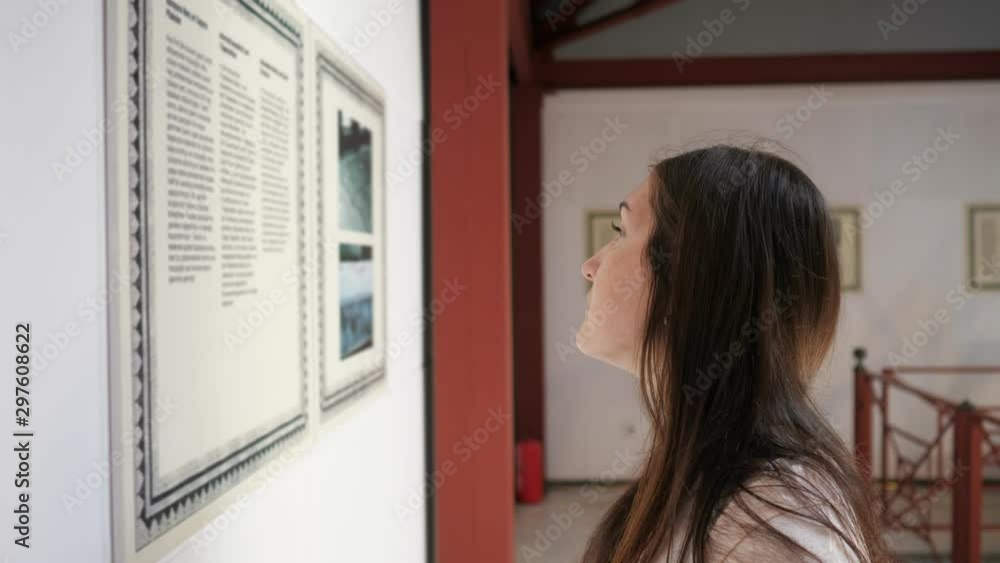 concentrated woman stands half face and reads information on poster in cultural Turkish museum closeup concentrated woman stands half face and reads information on poster in cultural Turkish museum closeup