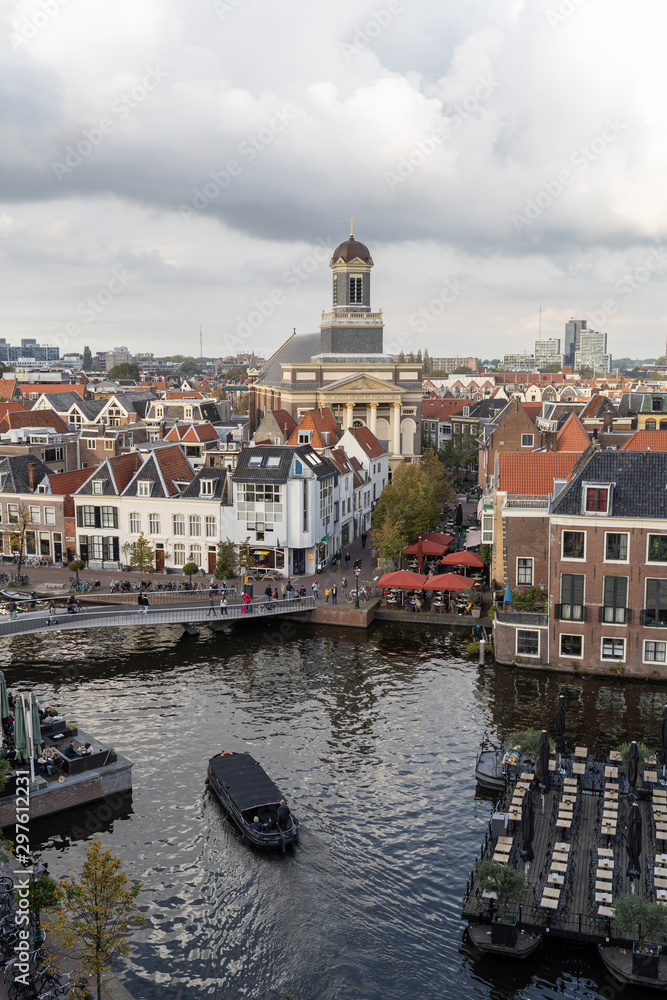 View of the Dutch city of Leiden. On the river Rijn the clouds above  and the floating terraces.  Hartebrugkerk in the background.