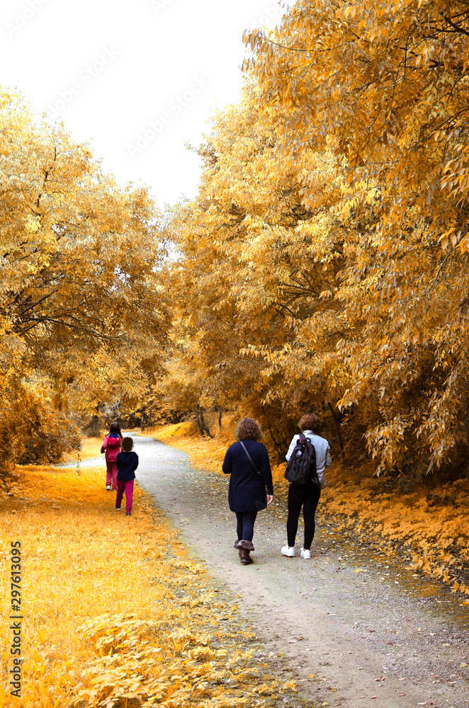 Fototapeta premium Family (two women and two girls) walking in a park in autumn. Oromana Park, Alcalá de Guadaira, Seville, Spain