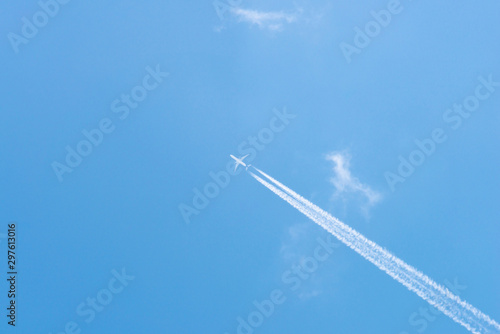 Airplane in a blue sky with clouds and condensation trails, Germany