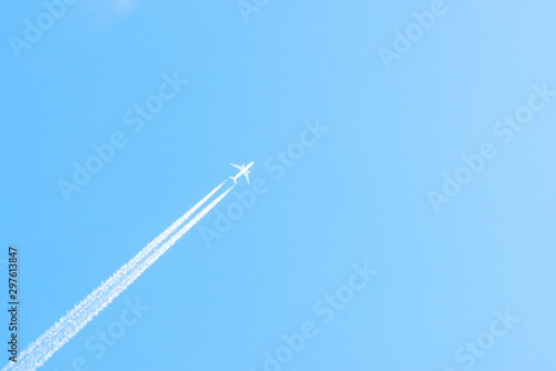 Airplane in a blue sky with clouds and condensation trails, Germany