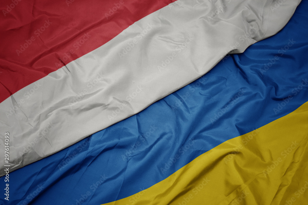 waving colorful flag of ukraine and national flag of indonesia. waving colorful flag of ukraine and national flag of indonesia.