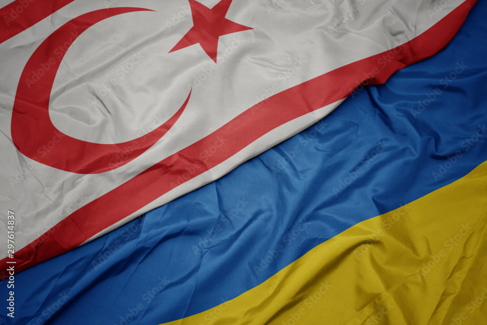 waving colorful flag of ukraine and national flag of northern cyprus.
