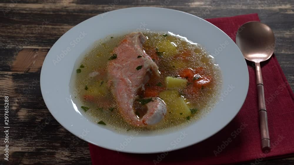 Fresh salmon fish soup with carrots, potatoes and herbs in a white plate, close up, rotates.Tasty dinner consists of a fish soup with salmon Fresh salmon fish soup with carrots, potatoes and herbs in a white plate, close up, rotates.Tasty dinner consists of a fish soup with salmon