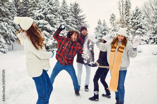 Young friends in winter coats having snowball fight in winter nature