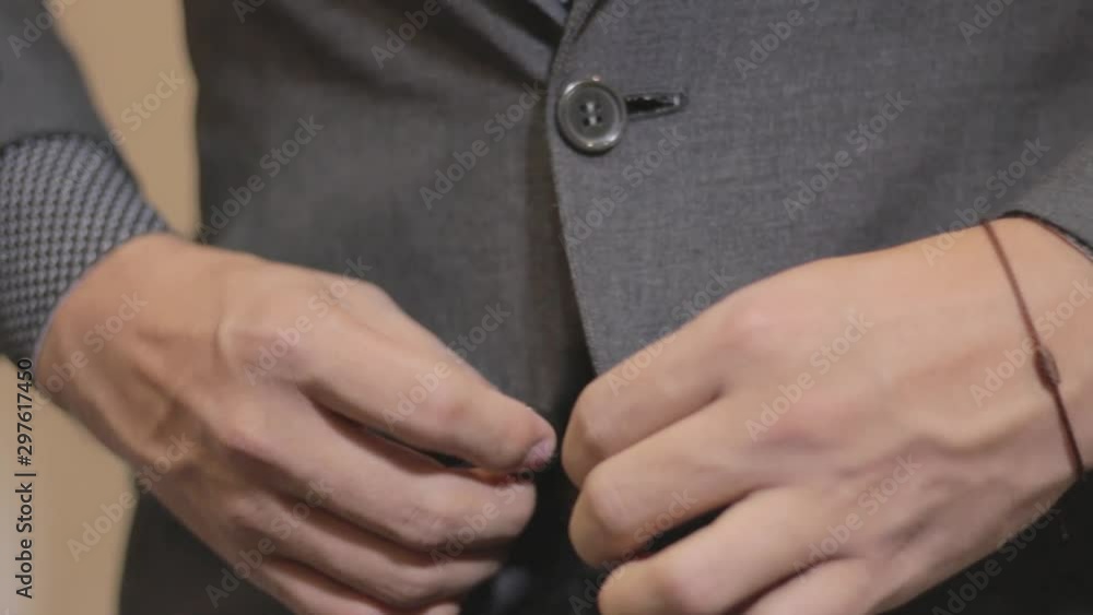 manos de hombre abrochando su saco 