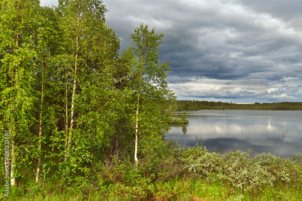 Picturesque northern forest lake with reflection of clouds in cold water in Finnish Lapland. Kuusamo