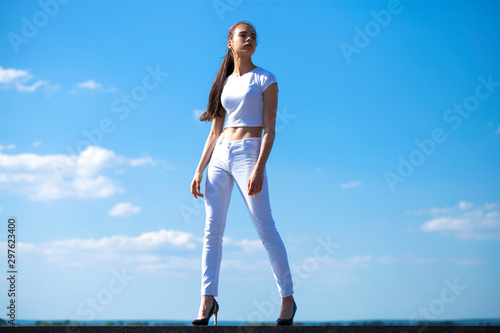 Beautiful brunette woman posing against blue sky bright sunny weather © Andrey_Arkusha