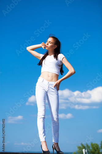 Beautiful brunette woman posing against blue sky bright sunny weather