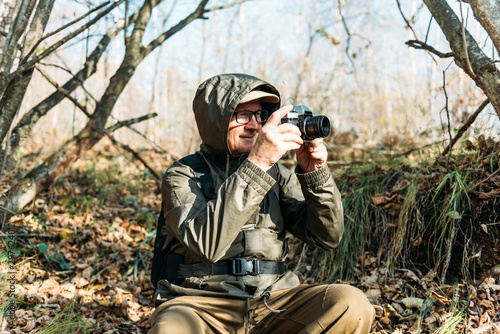 Mature man taking pictures of the forest in fall