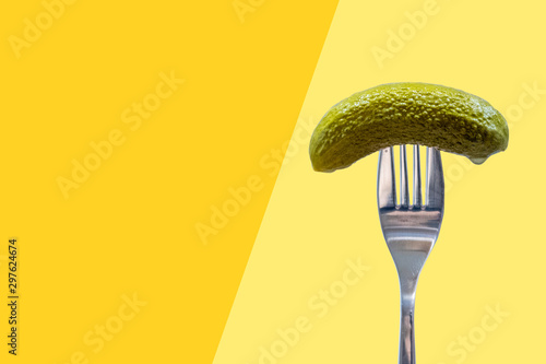 Pickle on fork, dill, gherkin, yellow and orange background, national pickle day 