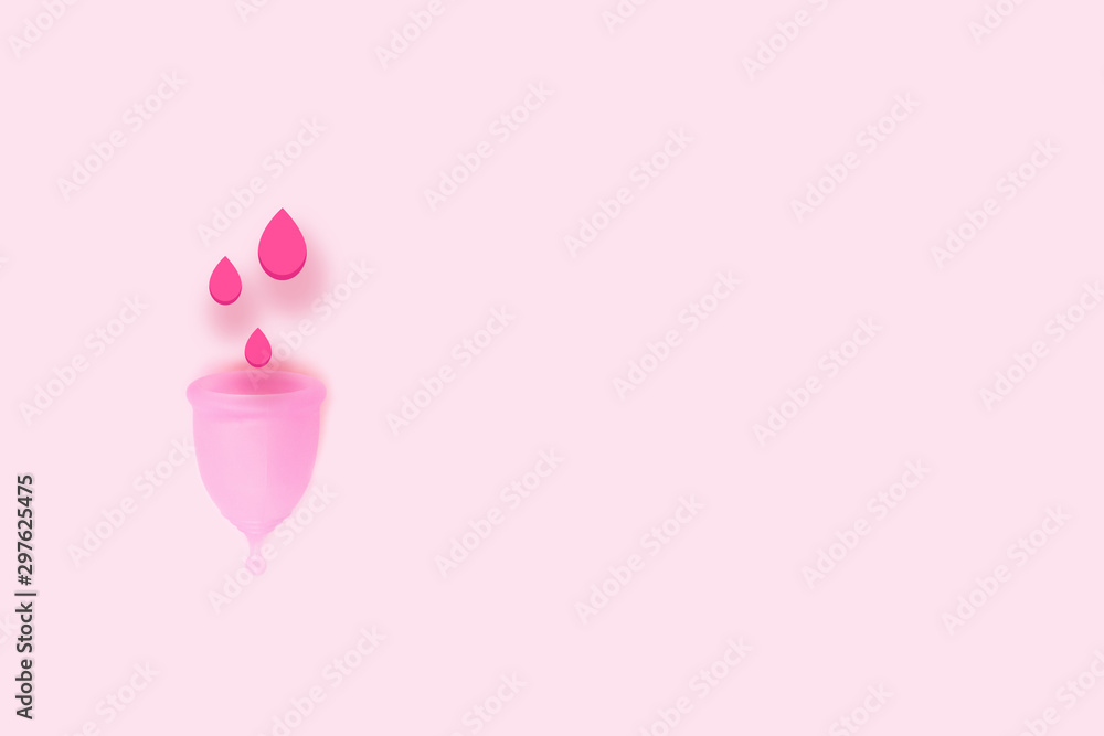 Pink menstrual cup with blood on pink background. Alternative feminine hygiene product during the period. Eco zero waste concept.