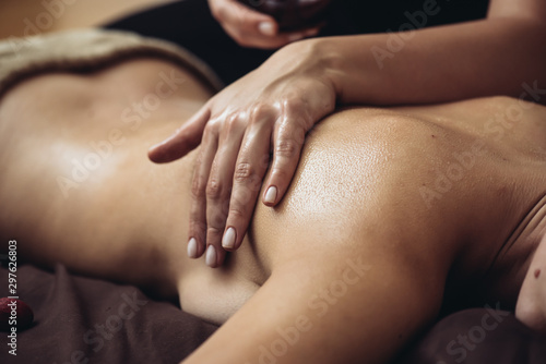 The massage therapist's hand spreads the body essential oil