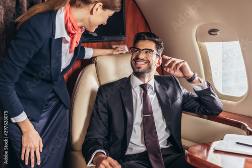 Tableau sur toile smiling businessman in suit looking at flight attendant in private plane