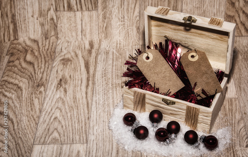 Imagen de Navidad con un fondo de madera, baúl  con espumillón rojo bolas rojas de navidad y 2 etiquetas  photo