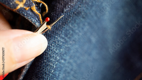 Hand rip out seam by handle seam ripper on  blue jeans fabric