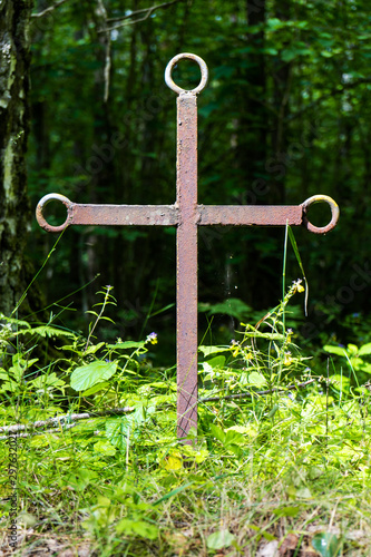 Metal catholic cross in the woods, forest build for commemoration. Unknown tomb.