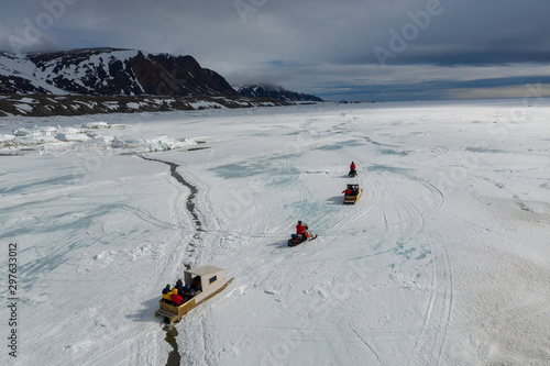 Obraz na płótnie Aerial drone photo of tourists travelling by Qamutiik on the sea ice near Sirmilik National Park in Nunavut, Canada w salonie